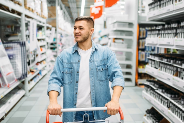 Male customer with trollley makes a purchase in market.