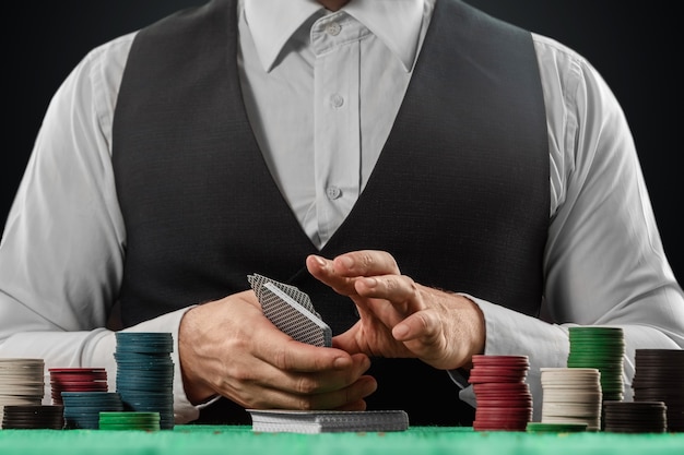 Male dealer at the casino at the table. Casino concept, gambling, poker, chips on the green casino table.