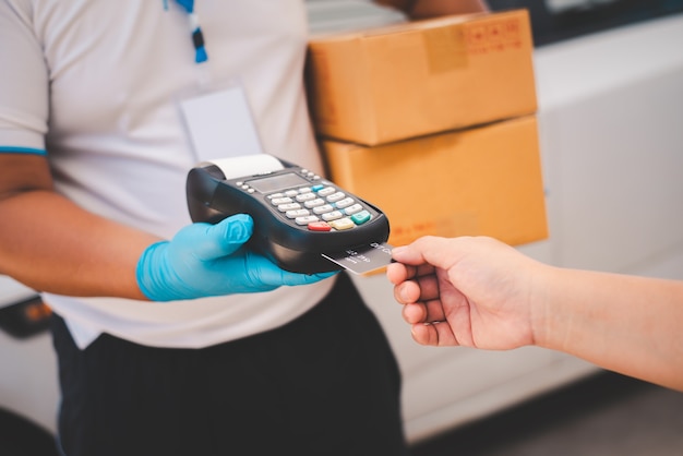 Male delivery workers wear sanitation faces and wear gloves, deliver goods or parcels, delivery service for users to pay via credit card for convenience and forgiveness during covid19.