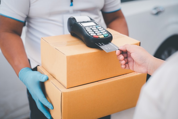 Male delivery workers wear sanitation faces and wear gloves, deliver goods or parcels, delivery service for users to pay via credit card for convenience and forgiveness during covid19.