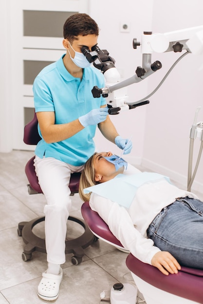 Male dentist examining woman looking on the teeth with professional microscope in the surgery dental office