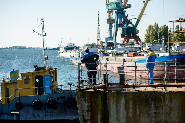 Male dock worker on the background of the shipyard and cranes