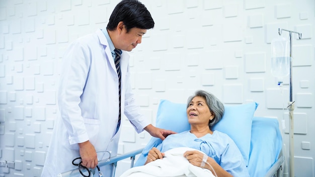 Male doctor came to inquire about the symptoms of an elderly female patient lying in bed receiving saline in the patient's room