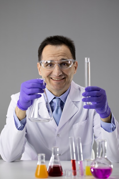 Male doctor or chemist blue gloves and protective glasses holding flask and tube