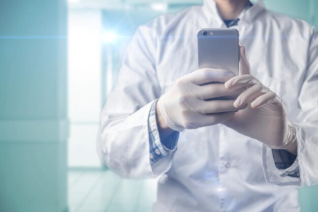 A male doctor in classic uniform holding and using a smartphone