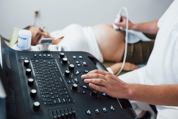 Photo male doctor does ultrasound for a pregnant woman in the hospital.