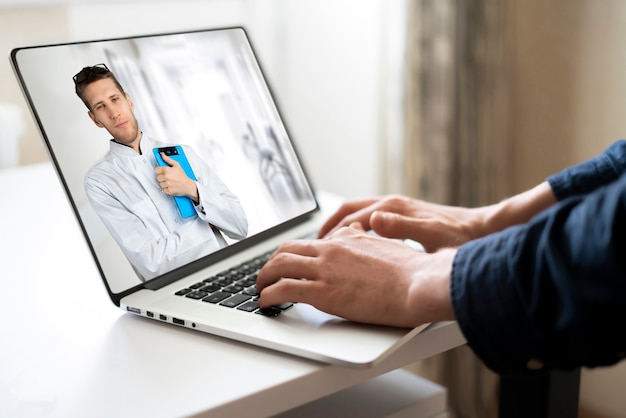 A male doctor doing examination on laptop webcam call online to the patient at home