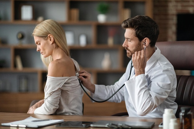 Male Doctor Doing Medical Check Up To Female Patient In Clinic