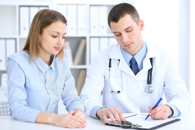 Male doctor  and  female patient sitting at the table in medical cabinet. High level and quality medical service concept.