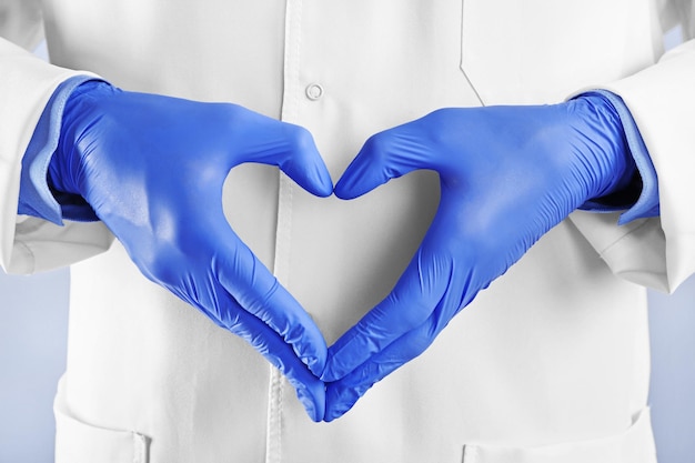 Male doctor hands in gloves making heart shape close up view