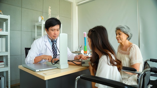 Male doctor is measuring blood pressure for a female patient using a pressure gauge and stethoscope for the diagnosis