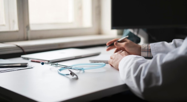 A male doctor sitting at the table and doing some work with patients in hospital