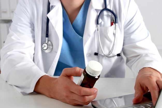 Male doctor sitting at the table and holding bottle