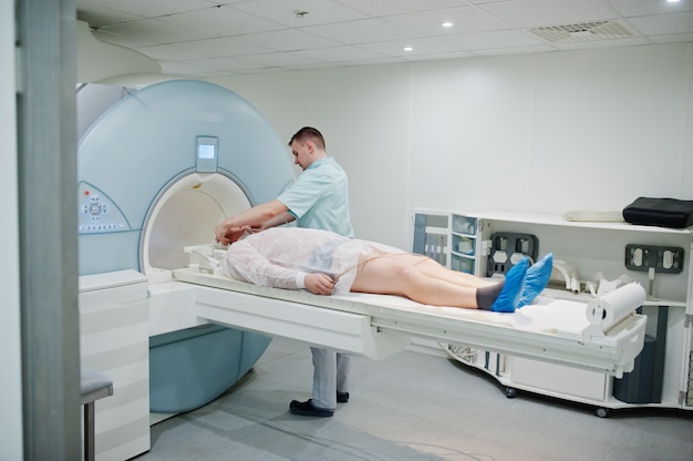 Male doctor turns on magnetic resonance imaging machine with patient inside.