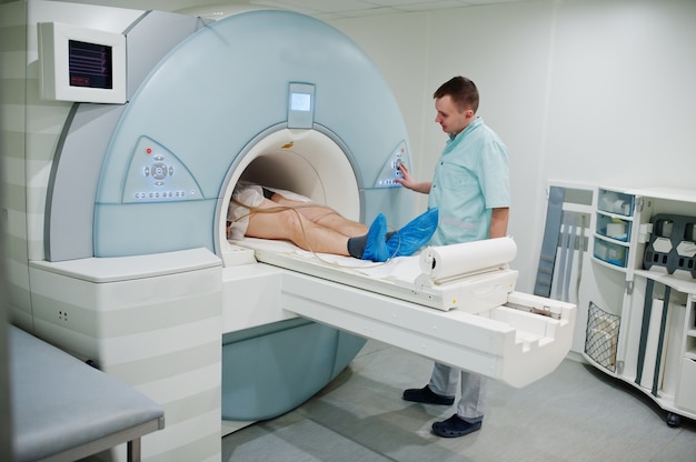 Male doctor turns on magnetic resonance imaging machine with patient inside.