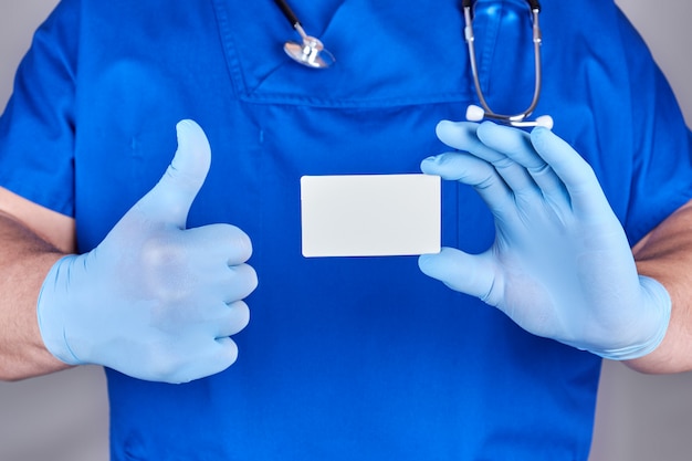 Male doctor wearing blue latex gloves is holding a blank paper business card