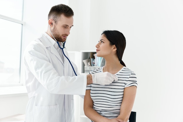 Male doctor in white coat examining female patient in hospital