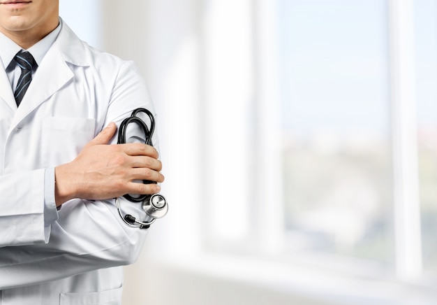 Male doctor with stethoscope on blurred hospital background