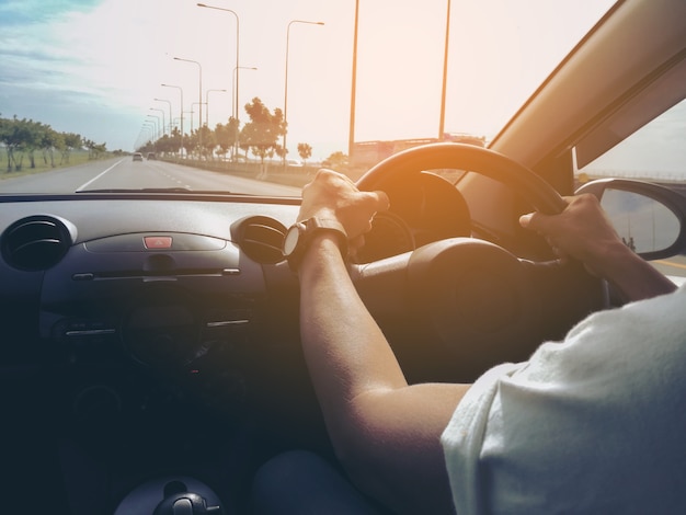 Male driver hands holding steering wheel