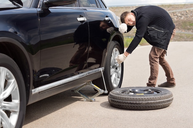 Male driver struggling to change his car tyre