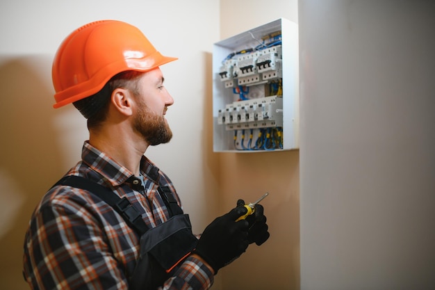 Photo a male electrician works in a switchboard with an electrical connecting cable