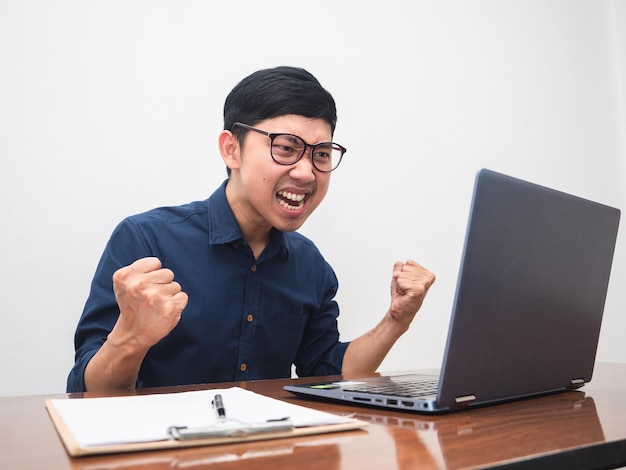 Male employee show fist up feels happy about successful with working on table