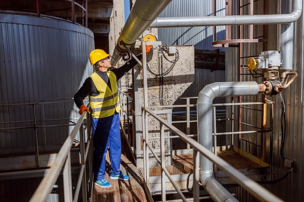 Male engineer checking metal pipe at factory