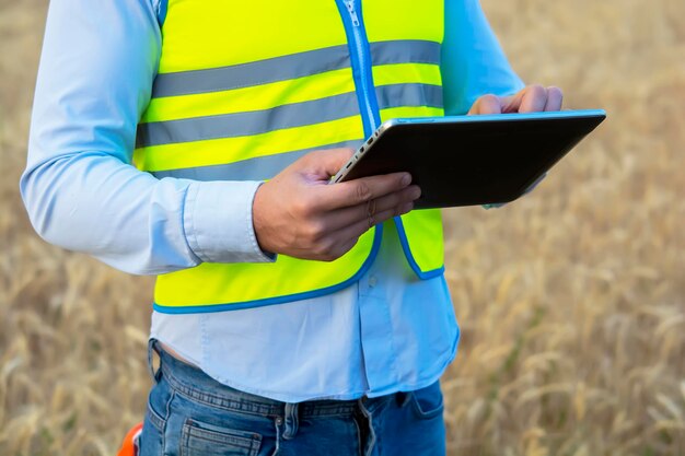 Male engineer in a helmet and goggles uses a smartphone for field work near a telecommunications tow