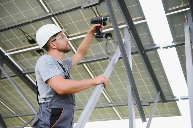 Male engineer in protective helmet installing solar photovoltaic panel system Alternative energy ecological concept