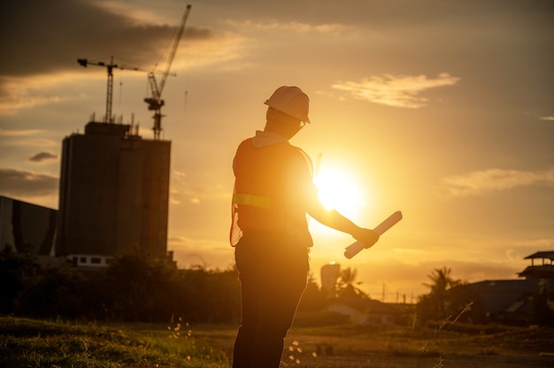 Photo male engineer working construction site at silhouette sunset time