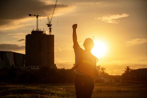 Photo male engineer working construction site at silhouette sunset time