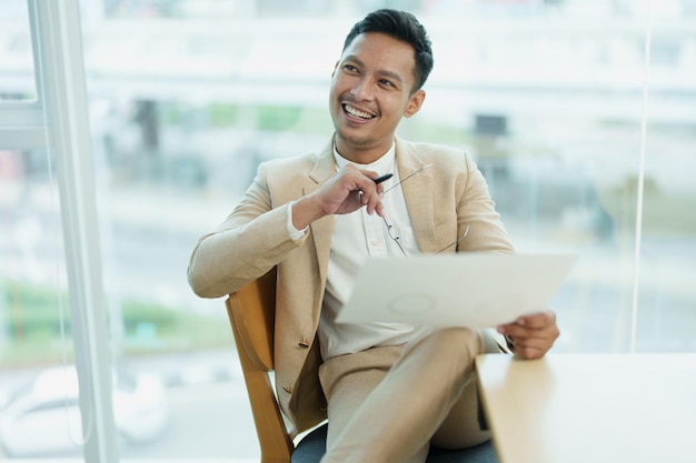 Male entrepreneur business owner or Asian male businessman sitting and holding documents at a meeting with smiling faces from work