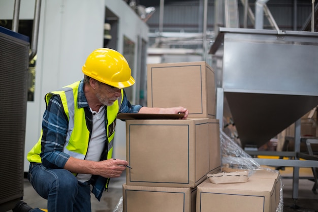 Male factory worker counting cardboard boxes