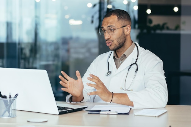 Male family doctor uses laptop for video call and online consultation serious and concentrated