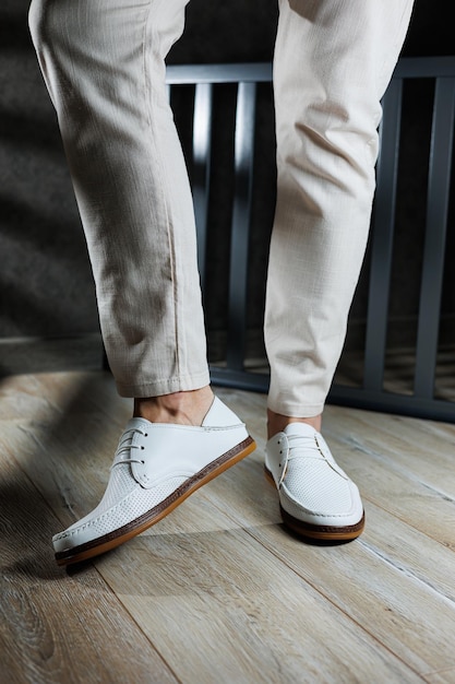 Photo male feet closeup in white casual shoes fashionable young man standing in leather stylish white moccasins in trousers seasonal summer men's shoes casual street style