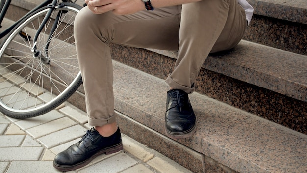 Male feet and vintage bicycle on stone stairs on city street.