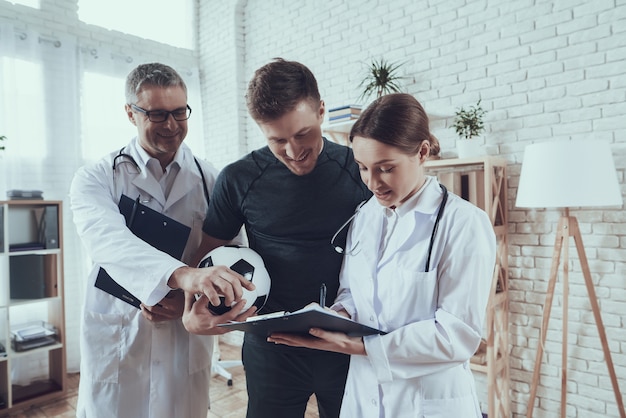 Male and female doctors are talking to football player