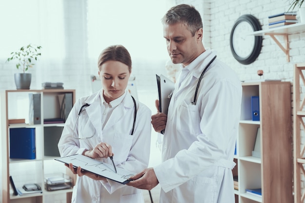 Male and female doctors with stethoscopes in office. Doctors are comparing notes.