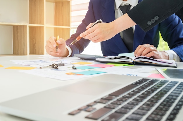 Male and female employees are analyzing data from graphs and taking notes