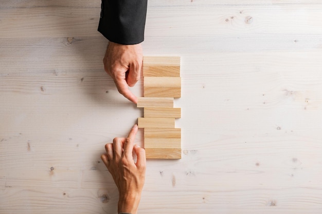 Male and female hands pushing two blank wooden pegs into a stack of them