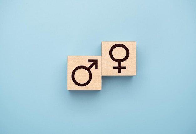 Male and female icon symbols on wooden blocks against blue background Top view Male and female symbol on two wooden blocks