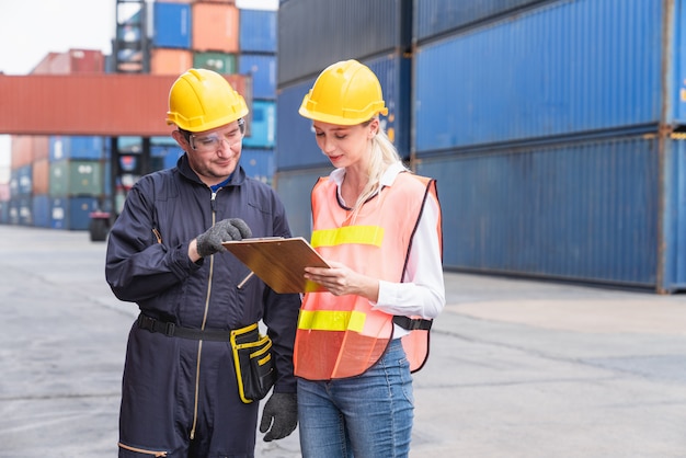 Male and female logistic staffs looking checklist Containers box documents at from Cargo freight ship at Cargo container shipping