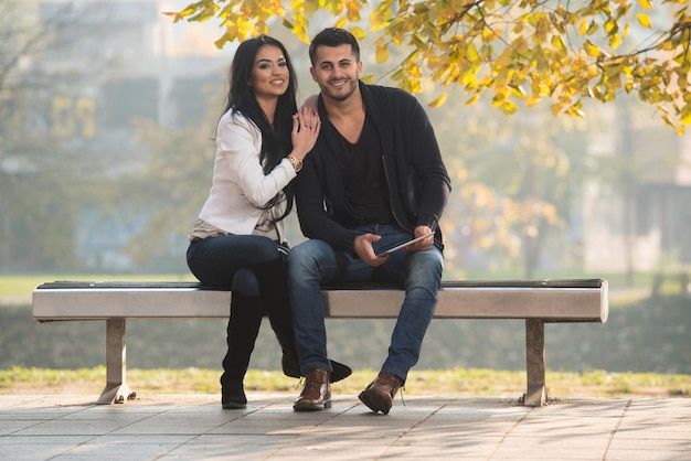 Male And Female Look At Electronic Tablet In Park