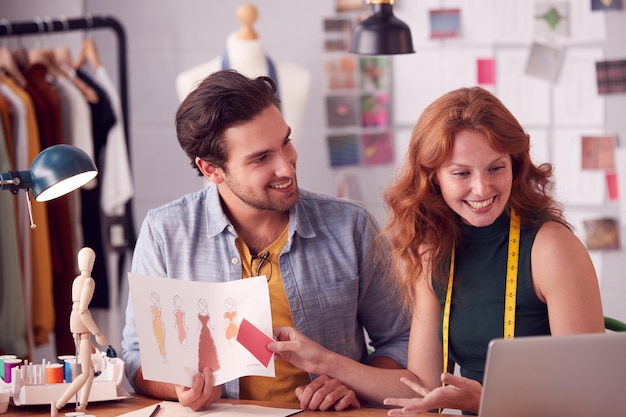 Male And Female Students Or Business Owners Working On Designs In Fashion Studio Together