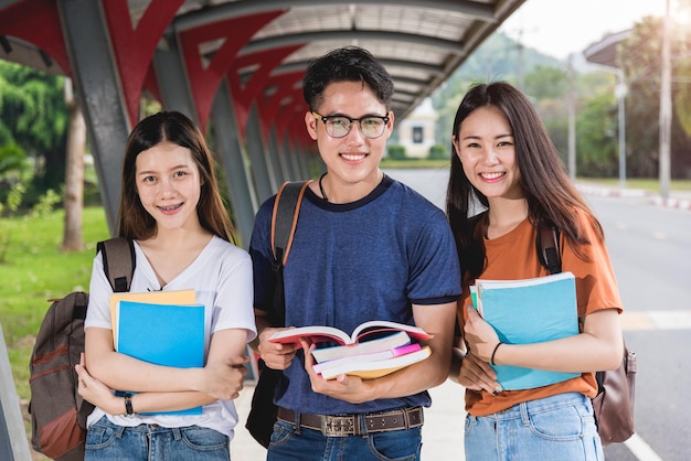 Male and female students stand on books and laptop computers on campus, Education concept