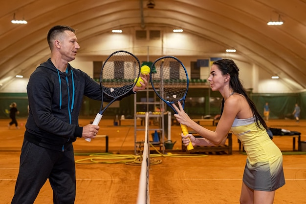 Male and female tennis players play a match on an indoor court