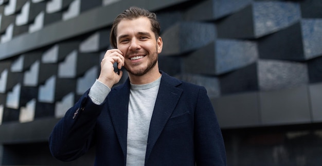 Male financial analyst confident talking on a mobile phone with a wide smile on the background of