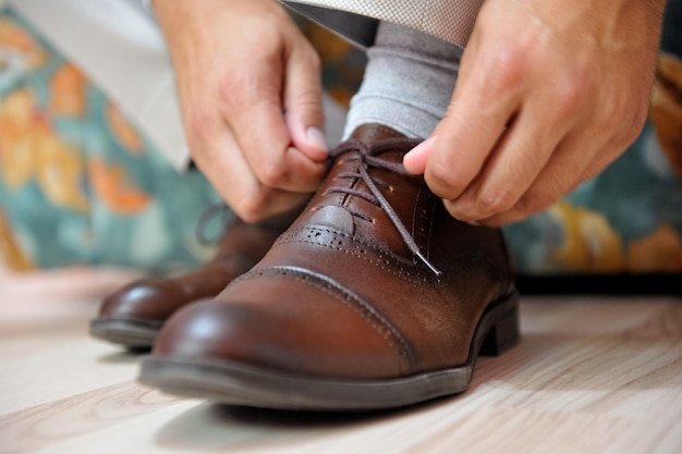 Male fixing the tie of his leather shoes