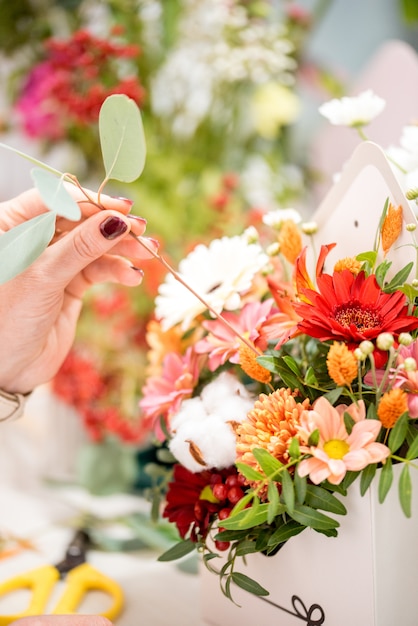 Male florist creating beautiful bouquet in flower shop, close up