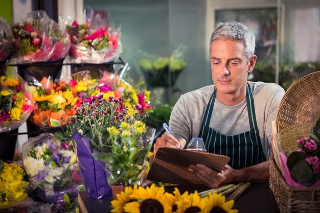 Male florist writing on clipboard